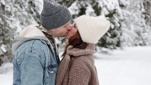 love and tenderness concept - close up of couple kissing in winter forest