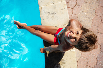 Photo of the ten years old boy sit on the side of the border of the swimming pool © Sergey Novikov