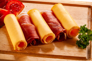 Yellow cheese and smoked ham on cutting board on white background
