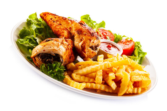 Stuffed chicken fillets, French fries and fresh vegetables
on white background