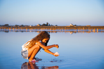 A little beautiful girl with beautiful flowing hair looks at salt in a transparent watery glaze on a transparent background