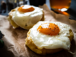 Continental breakfast - sunny side up eggs on baked bun with cheese and vegetable salad on black background
