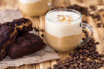 Hot Cup of latte and a chocolate muffin on wooden background.