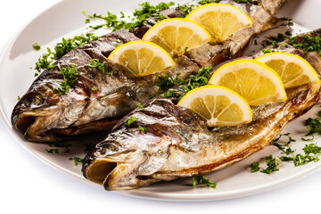Fish dish - roasted trout with lemon on white background

