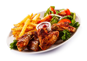 Roast chicken wings with curly fries and vegetable salad on white background
