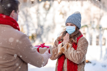 Lady in face mask getting present from man, standing outdoors