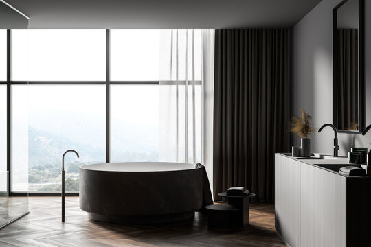Dark gray bathroom interior with round tub and sink, side view