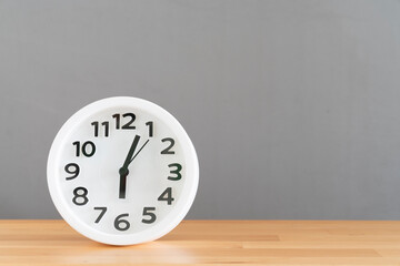 Retro white alarm clock on wooden table with gray background, vintage style