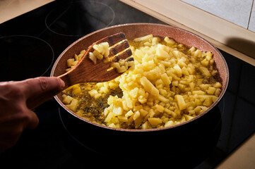 Chopped potatoes frying in extra virgin olive oil in the pan to