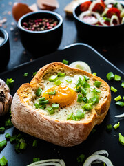 Continental breakfast - sunny side up egg in baked bun with cheese and vegetable salad on black 