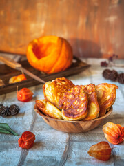 Obraz na płótnie Canvas Pumpkin pancakes in a deep plate and cut pumpkin on the drill table