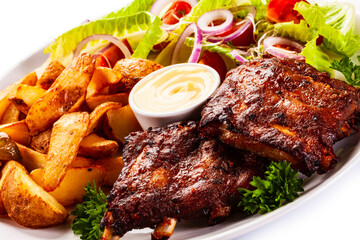 Tasty roasted ribs with baked potatoes vegetables on white background
