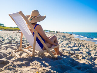 Woman relaxing on beach sitting on sunbed
