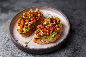 
bruschetta with avocado, chickpeas and microgreens on a dark background
