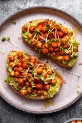 
bruschetta with avocado, chickpeas and microgreens on a dark background