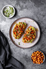 
bruschetta with avocado, chickpeas and microgreens on a dark background
