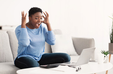 Fototapeta na wymiar Black woman using laptop celebrating success screaming yes