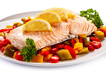Roast salmon steak with mix of vegetables served on white background