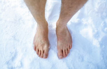 Top view of male feet standing on snow outdoors, cropped. Unrecognizable guy making cold exposure training