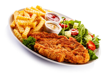 Breaded fried pork chop, French fries and vegetables on white background
