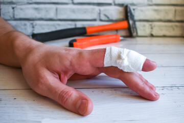 bandaged finger on worker's hand. An accident at work - bandaging man's injured finger. Hand with...