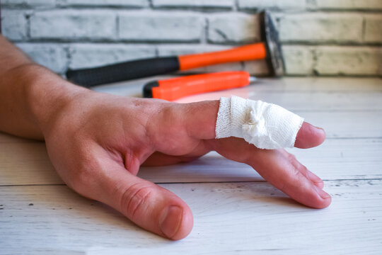 bandaged finger on worker's hand. An accident at work - bandaging man's injured finger. Hand with bandaged finger on background of working tools.