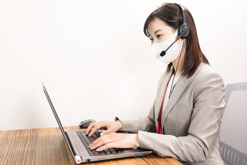 Woman wearing a headset with mask and having a web conference