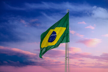 Bandeira do Brasil hasteada e tremulando com o vento e céu com nuvens ao fundo. - obrazy, fototapety, plakaty