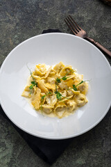 Tortellini with duck, croutons and cheese sauce on a white plate