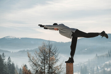 Man practicing yoga and balancing exercises in the winter mountains and enjoying life. Copy, empty space for text