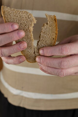 A man's hand splits a slice of rye bread in two.