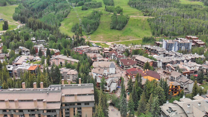 Fototapeta premium Vail city center and surrounding mountains, Colorado. Aerial view from drone in summer season