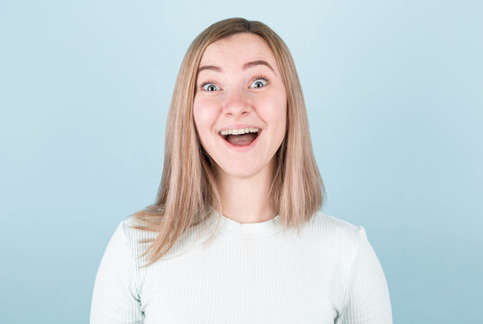 Young woman very surprised looking at the camera. Surprise and shopping concept on blue background.