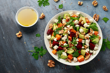 Healthy Butternut squash salad with beetroot, avocado, walnut and feta cheese in white bowl