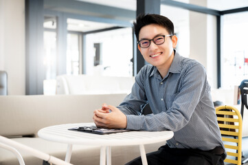 Happy young man sitting in modern office and  looking at the camera with smile