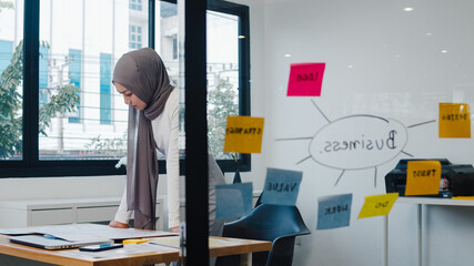 Asia muslim lady drawing work plan think information reminder on paper in new normal office....