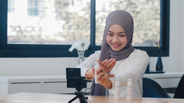 Beauty blogger present beauty cosmetics sitting in front camera for recording video. Beautiful young Asian muslim woman use cosmetics review make up tutorial broadcast live video to social network.