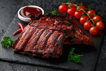 Grilled pork ribs with bbq sauce and herbs on stone board