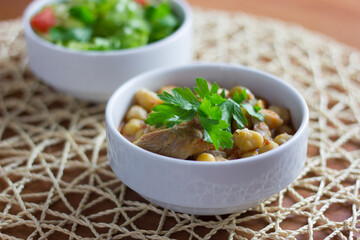 Chickpeas with meat in a white bowl with parsley