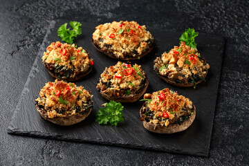 Stuffed mushrooms with spinach, bread crumbs and cheese on stone board