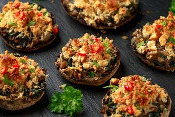 Stuffed mushrooms with spinach, bread crumbs and cheese on stone board