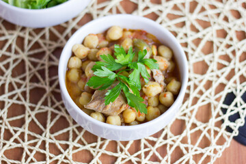 Chickpeas with meat in a white bowl with parsley
