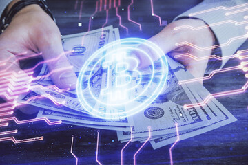 Multi exposure of blockchain theme drawing hologram and USA dollars bills and man hands. Business concept.