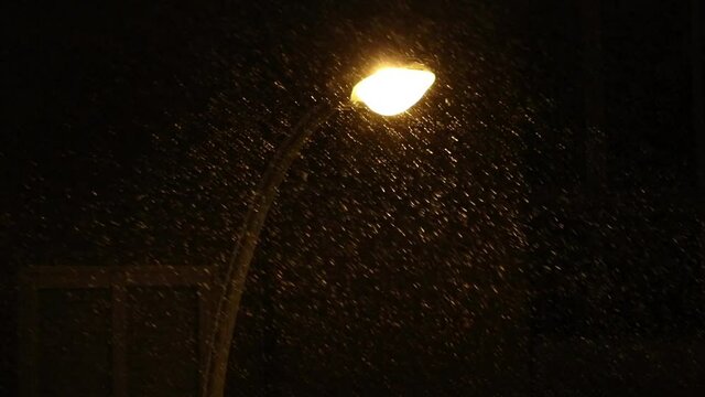 now falling in front of the street lamps at winter night