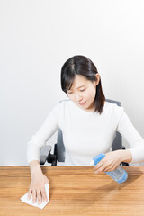 Fototapeta na wymiar Woman disinfecting desk with alcohol