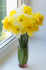 A beautiful, spring bouquet of daffodils on the window.