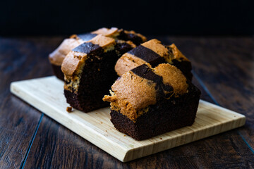 Homemade Whole Sliced Zebra Cake with Chocolate on Wooden Board.