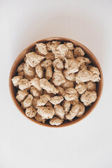 Raw dehydrated soy meat or dry soya chunks in wooden plate on white background. Top view. Copy, empty space for text