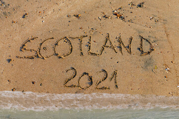 Scotland 2021 in Sand geschrieben , wasser überspült den Sand
