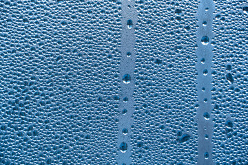 Abstract background ornament with water drops.Raindrops on the glass in rainy weather.The glittering, shiny surface of water on glass.Water drops in the form of balls or spheres.Blue raindrops